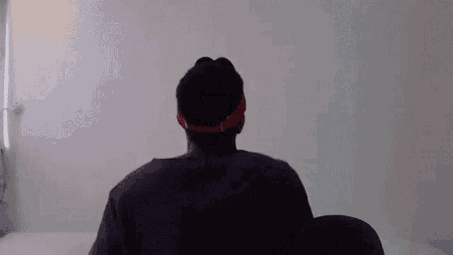 a man is sitting on a bed wearing headphones and a red headband .