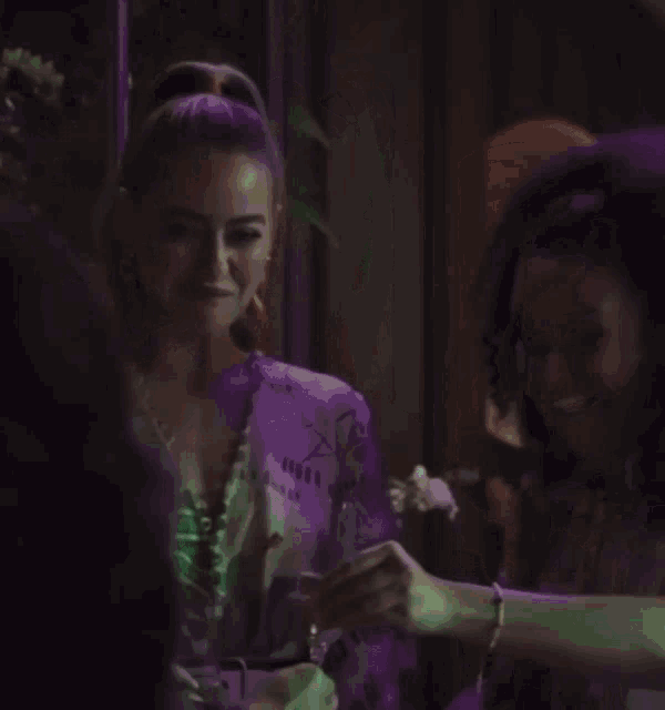 two women are standing next to each other in a dark room