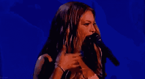 a woman in a pink dress is singing into a microphone on a stage .