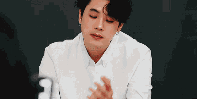 a man in a white shirt has his hands folded