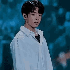 a young man in a white shirt is standing in front of a crowd .