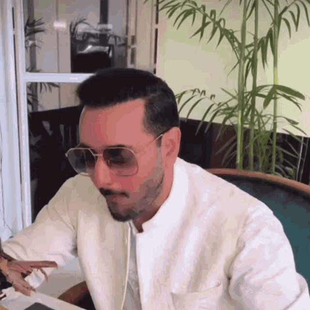 a man wearing sunglasses and a white jacket is sitting at a table