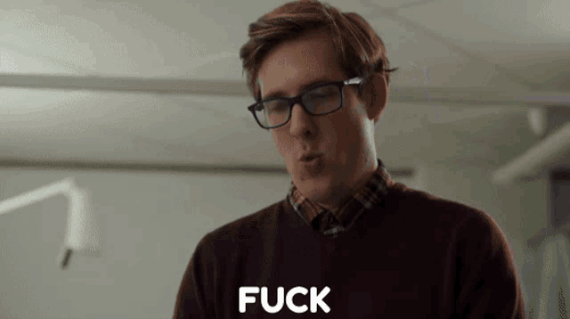 a man wearing glasses says the word fuck in front of him