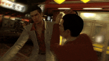 a man in a white suit is standing next to another man in a red sweater