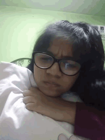 a girl wearing glasses is laying in bed