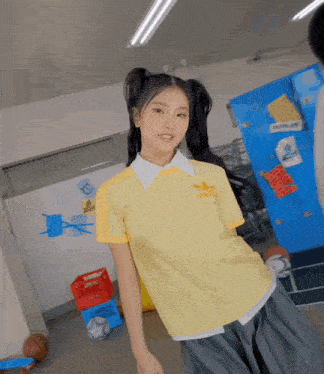 a girl wearing a yellow adidas shirt and gray skirt
