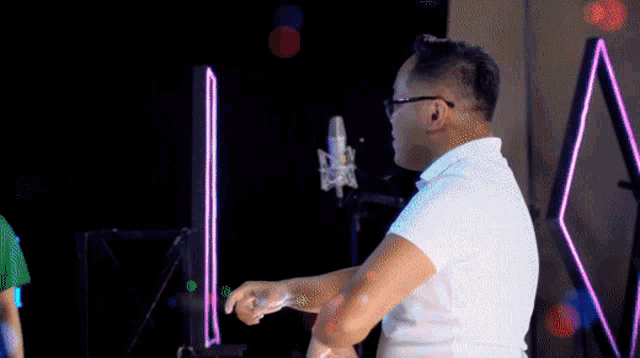 a man wearing glasses and a white shirt is standing in front of a microphone