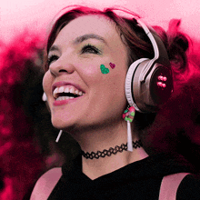 a woman wearing headphones and a choker smiles