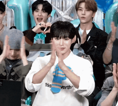 a group of young men are clapping and making a heart shape with their hands