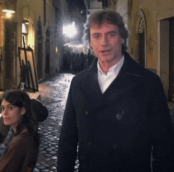 a man in a black coat stands next to a woman in a brown coat