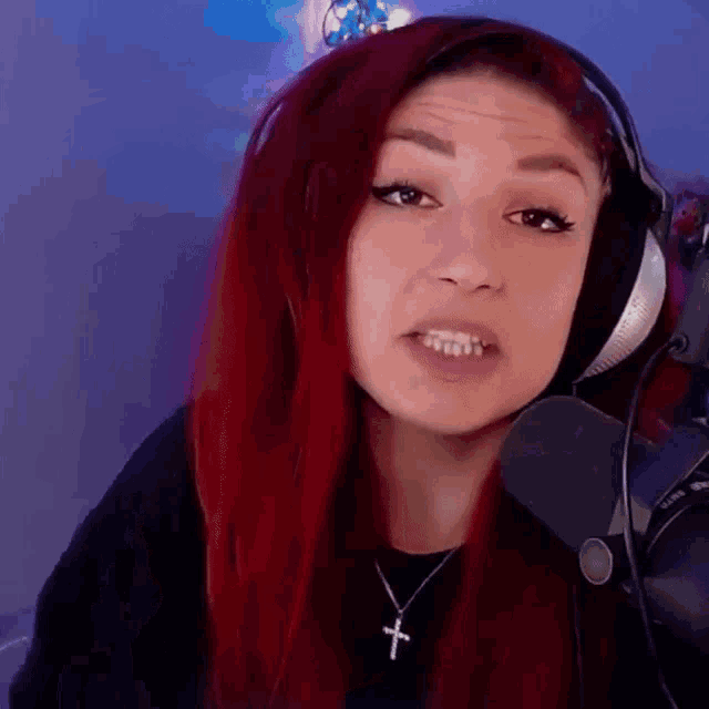 a woman with red hair is wearing headphones and a necklace with a cross