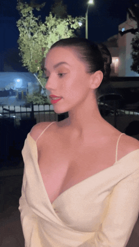 a woman with a very plunging neckline is standing in front of a building at night