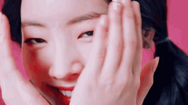 a close up of a woman covering her face with her hands while smiling .
