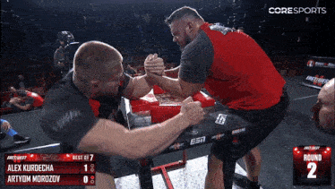 two men arm wrestling in front of a scoreboard that says " coresports "