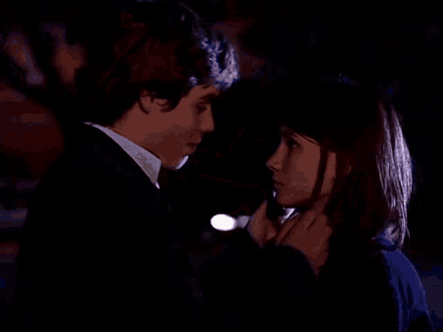 a man and a woman are touching each other 's faces in the dark