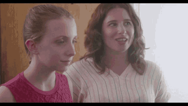a woman and a girl are standing next to each other and talking .