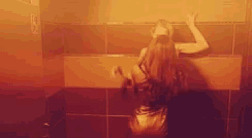 a woman is leaning against a wall in a bathroom in a dark room .