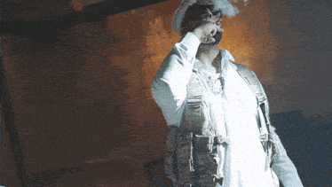 a man wearing a white shirt and a military vest smoking a cigarette
