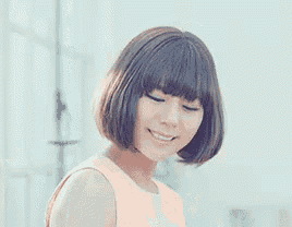a woman with a bob hairstyle and bangs is smiling .