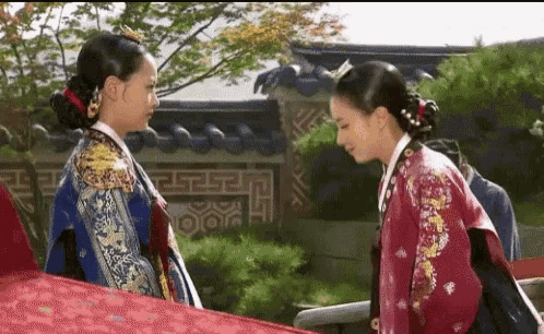 two women in traditional korean clothing are standing next to each other .