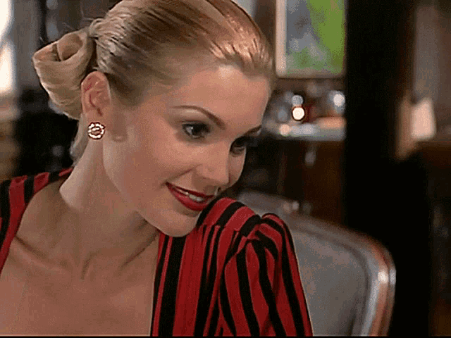 a woman wearing a red and black striped dress and earrings