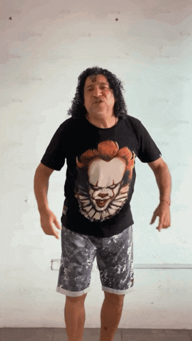 a man with curly hair is wearing a pennywise shirt and shorts