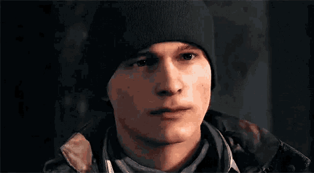 a man wearing a beanie and a scarf is looking at the camera .