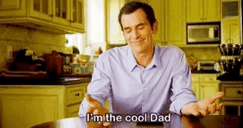 a man is sitting at a table in a kitchen talking about being the cool dad .