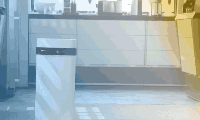 a white trash can in a kitchen with the letter g on the top