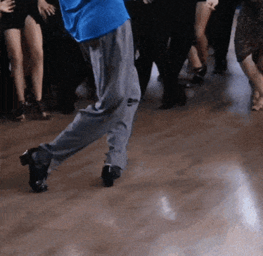 a man in a blue shirt is dancing on a wood floor