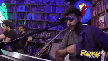a man singing into a microphone in front of a roxy bar