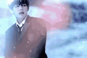 a man in a suit and tie is standing in the snow with his tongue hanging out .