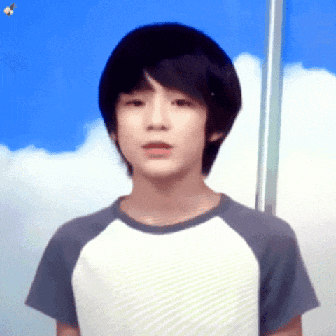 a young boy wearing a gray and white shirt stands in front of a blue sky with clouds
