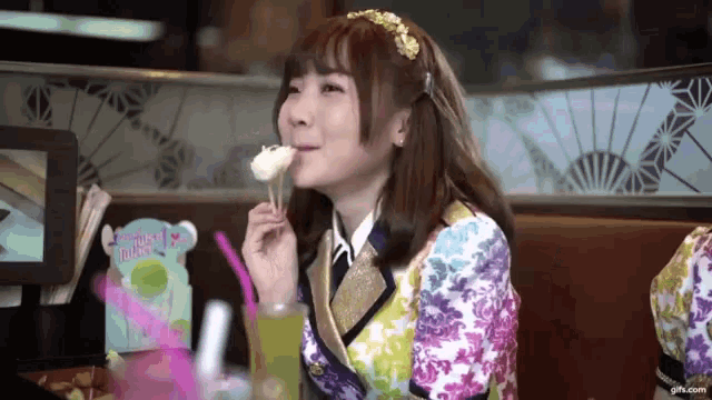 a girl in a floral dress is eating a piece of food