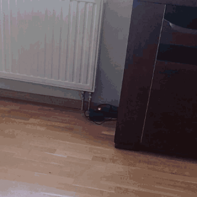 a white radiator sits on a wooden floor next to a cabinet