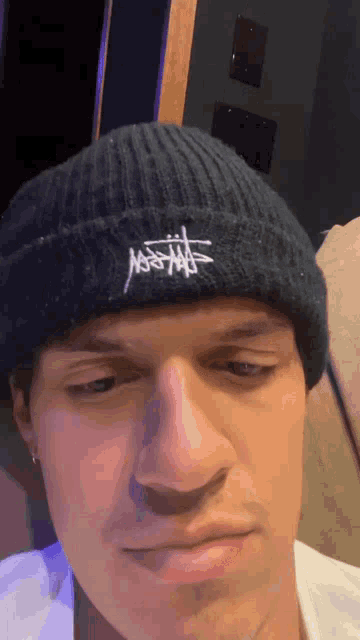 a close up of a man wearing a black beanie with a s on it
