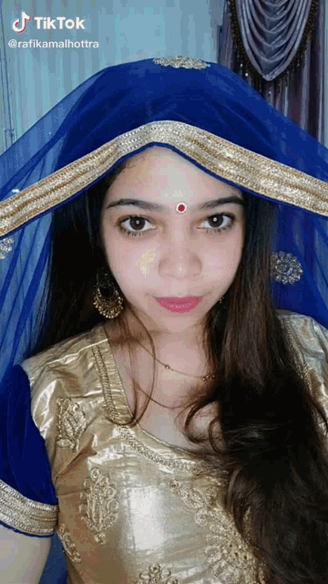 a tiktok video of a woman wearing a blue and gold veil