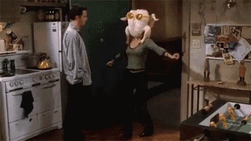 a woman is holding a turkey on her head while dancing in a kitchen .