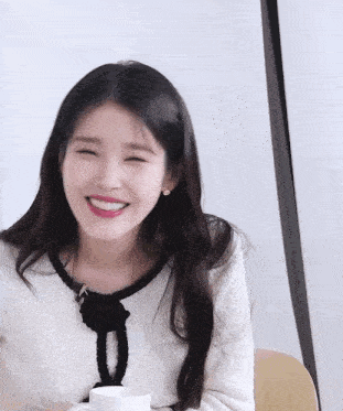 a woman in a white sweater is smiling while holding a cup of coffee