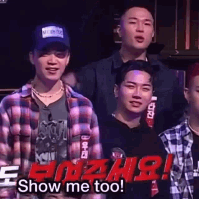 a group of young men are standing next to each other in a room and one of them is wearing a plaid shirt .