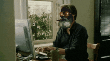 a man with a beard and goggles is typing on a laptop