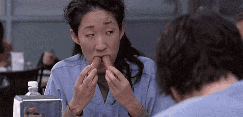 a woman is eating a hot dog next to a man in a restaurant .