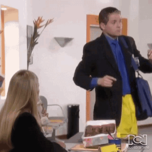 a man in a suit and tie is standing next to a woman in a waiting room