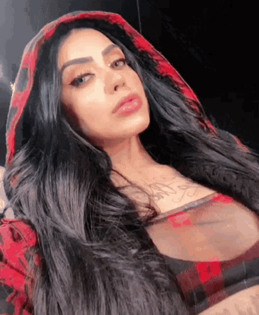 a woman with long dark hair is wearing a red plaid hoodie