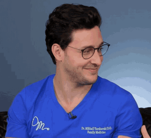 a man wearing glasses and a blue shirt that says " dr. mikhail varshavski d.o. family medicine "