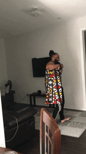 a woman is standing in a living room holding a blanket with a pattern of triangles
