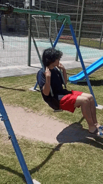 a person is swinging on a swing set with a blue slide in the background
