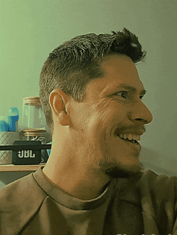 a man in a brown shirt is smiling in front of a black jbl speaker