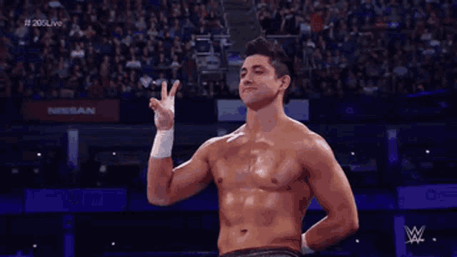 a man without a shirt is standing in front of a crowd with a nissan sign in the background