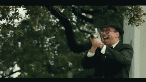 a man in a top hat is taking a picture of a tree .